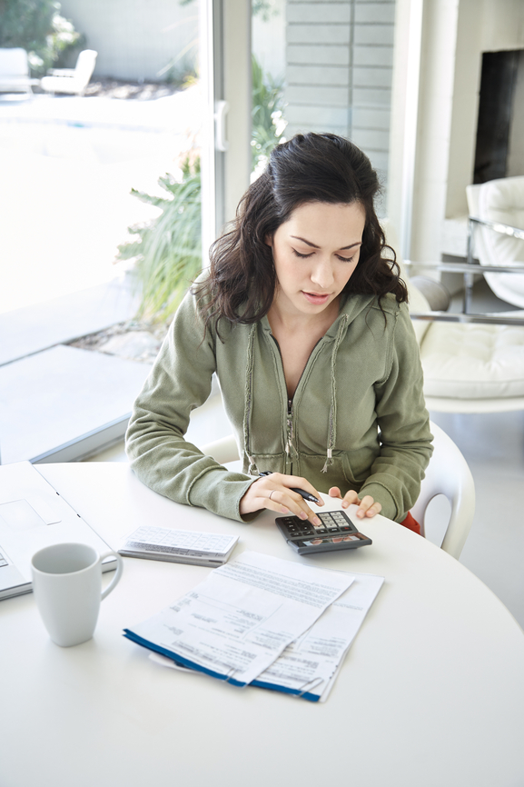 Woman calculating savings when using a home equity loan to pay off debt.